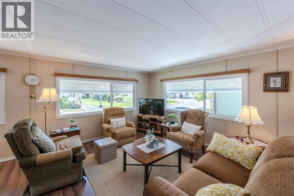 Living room with beige sofas, armchairs, a coffee table, and windows. - 999 Burnaby Avenue Unit# 66, Penticton