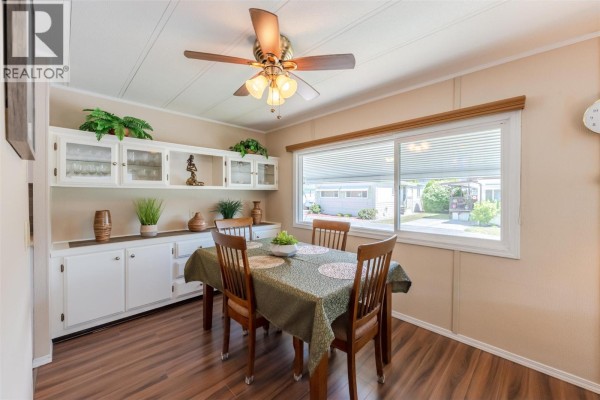Dining area with a wooden table, chairs, and a white built-in buffet. - 999 Burnaby Avenue Unit# 66, Penticton