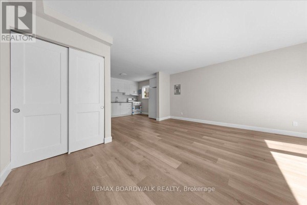 Living room with light wood laminate flooring and a white bi-fold closet door. - 999 Meadowlands Drive, Ottawa