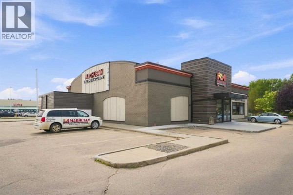 Side view of a commercial building with "Madhuban Fine Indian Cuisine" signage and parked cars. - 9995 178 Street Nw, Edmonton