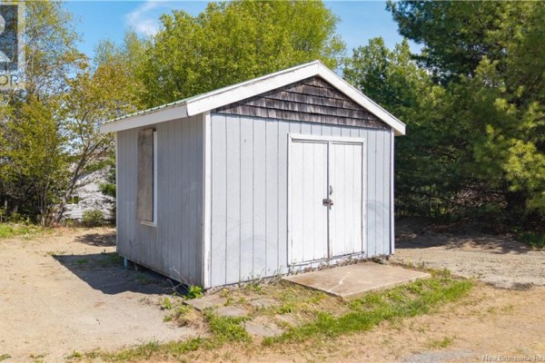 Small light blue shed with a wooden shingle roof and double doors. - 99a Glebe Road, Chamcook