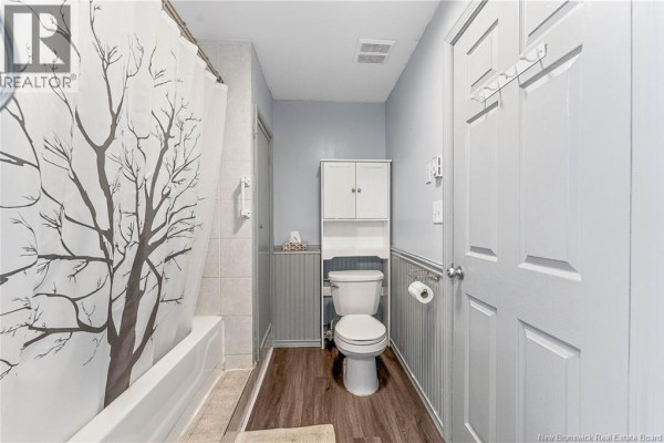 Bathroom with a bathtub, toilet, vanity, and a tree-patterned shower curtain. - 99a Glebe Road, Chamcook