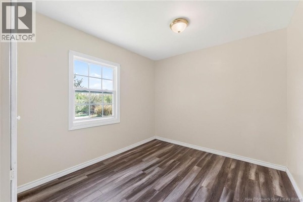 Empty room with light beige walls, a single window, and dark wood laminate flooring. - 99a Glebe Road, Chamcook
