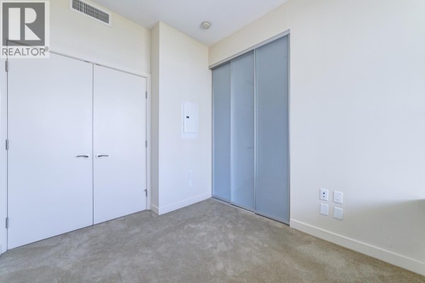 Carpeted room with closet doors and sliding frosted glass doors. - 9xx 6383 Mckay Avenue, Burnaby