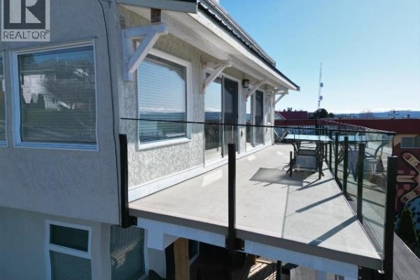 Close-up of the upper deck with glass railing and lounge chairs, bright sunny day. - A, B, C-6848 Courtenay Street, Powell River
