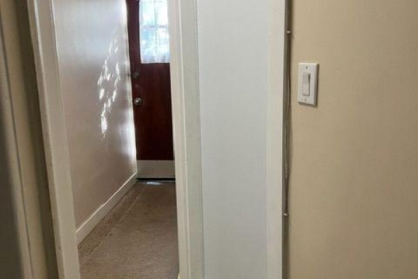 View down a hallway showing a wooden door and light filtering through a window. - A - 11 Kippewa Drive, Ottawa