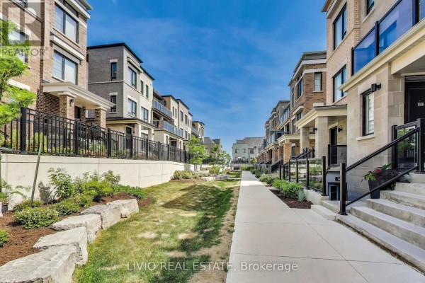 Pathway between townhouses with landscaped greenery and stone features - A - 14 Lookout Drive, Clarington