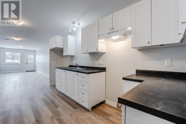 White kitchen cabinets with black countertops and stainless steel appliances, overlooking the living area. - A - 15 William Street, North Stormont
