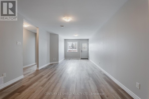Living area with light grey walls, wood-look flooring, and a doorway leading outside. - A - 15 William Street, North Stormont