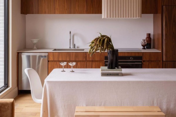 Close-up of a kitchen area with wood cabinets, stainless steel dishwasher, and a white table with champagne glasses. - A - 157 Hallam Street, Toronto
