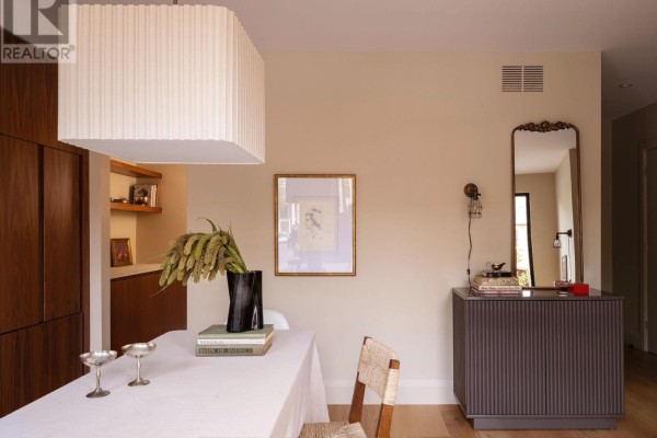 Dining area with a white tablecloth-covered table, a framed picture on a beige wall, and a dark gray cabinet. - A - 157 Hallam Street, Toronto