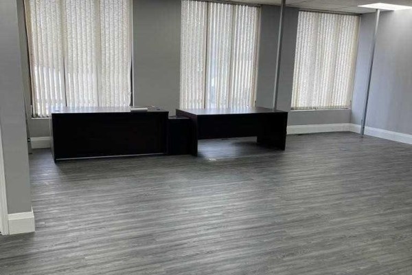 Interior office space with grey walls and flooring, featuring two dark desks. - A - 1880 Bonhill Road, Mississauga