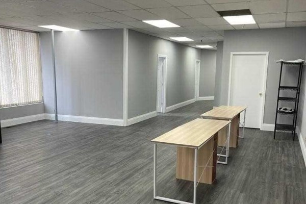 Hallway in commercial space with grey walls, grey wood-look flooring, and multiple doors. - A - 1880 Bonhill Road, Mississauga