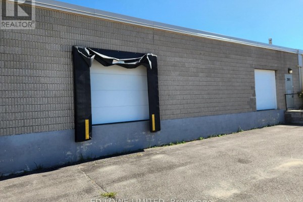 Exterior view of commercial building with a loading dock door and a side entrance door. - A - 201 Bay Street, Midland