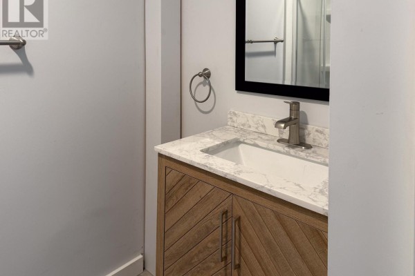 Bathroom vanity with a white sink, marble-look countertop, and wood-grain cabinets. - A - 23 Peter Street S, Orillia