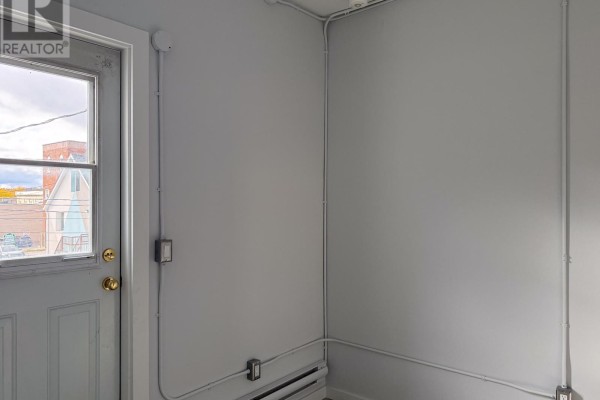 Interior room with a window showing buildings, and a white door with gold hardware. - A - 23 Peter Street S, Orillia