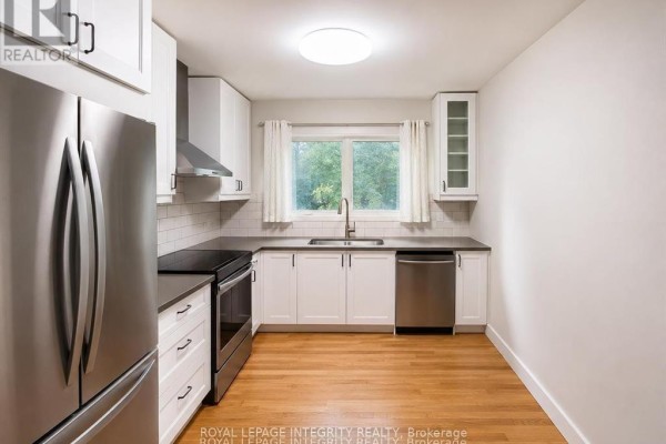 Bedroom with light wood floors, large white bookshelves, and gray curtains covering a window. - A - 2748 Moncton Road, Ottawa