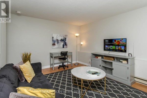 Living area with sofa, coffee table, desk, and television against a light-colored wall. - A - 276 Carruthers Avenue, Ottawa