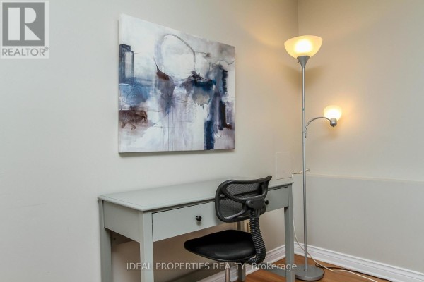 Close-up of a grey desk and chair with abstract wall art and a floor lamp. - A - 276 Carruthers Avenue, Ottawa