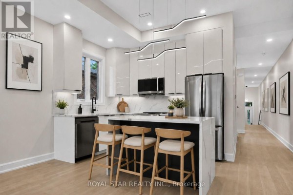 Contemporary kitchen with white cabinets, black countertops, island with stools, and stainless steel appliances. - A - 526 Mutual Street, Ottawa