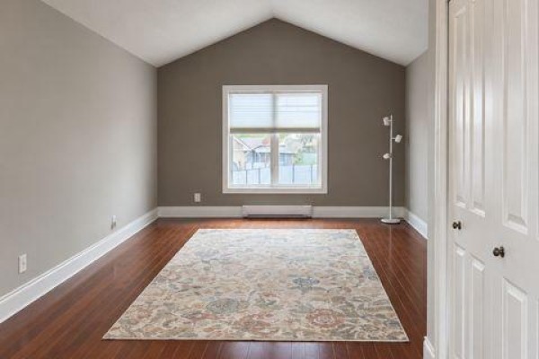 Room with vaulted ceiling, hardwood floors, large rug, and window overlooking view. - A - 9 Francis Street W, Kawartha Lakes