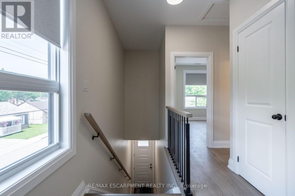 A modern kitchen features white cabinets, stainless steel appliances, and a black countertop. - A - 9 Munn Street, Hamilton