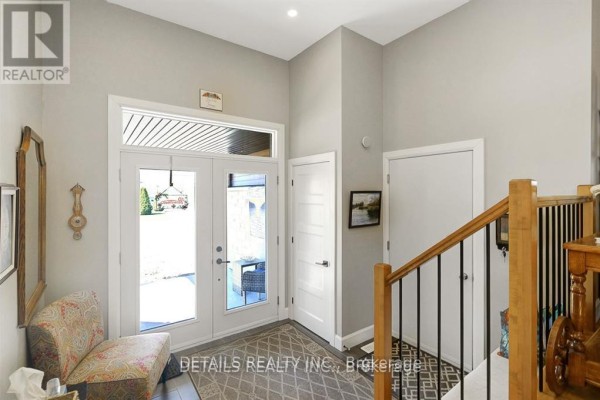 Main entrance hallway with double glass doors, patterned rug, and wood staircase. - A - Upper Unit - 2565a Page Road, Ottawa