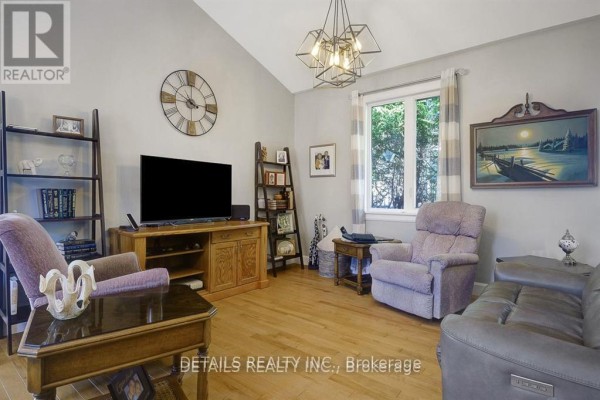 Living room with wood floors, plush chairs, television, and large window with striped curtains. - A - Upper Unit - 2565a Page Road, Ottawa