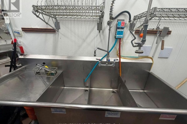 Commercial kitchen with stainless steel refrigerators, cooking equipment, and tiled floor. - A-11.5 - 2630 Simcoe Street N, Oshawa