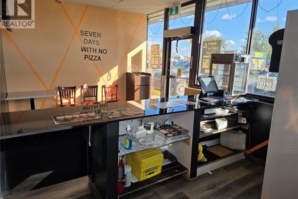 Counter area with a commercial pizza oven, display refrigerator, and storage shelves. - A 2740 Avonhurst Drive, Regina
