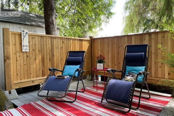 Covered swing with colorful plaid blanket, surrounded by chairs and a woodpile. - A-6 10324 Lakeshore Rd, Port Alberni
