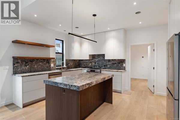Contemporary kitchen with white cabinets, a marble island, and wood shelving. - A 9650 Third St, Sidney