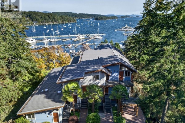 Aerial view of the blue and grey multi-family building with a marina and boats in the background. - A-g 118 Rainbow Rd, Salt Spring