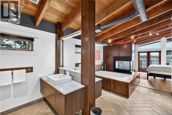 Bathroom with a double sink vanity, soaking tub, and view of the water from the bedroom. - A-g 118 Rainbow Rd, Salt Spring