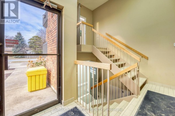 Interior entrance with glass door and a beige staircase with metal railings. - A-upper - 2695 Hamilton Road, Sarnia