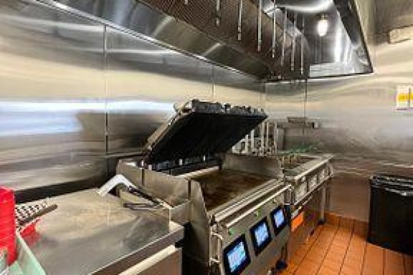 Commercial kitchen with stainless steel equipment and grill area. - A010 - 4543 Kingston Road, Toronto