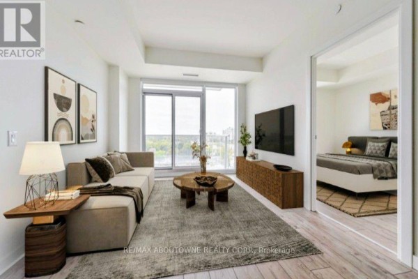 Living room with beige sectional sofa, wooden coffee table, and large window. - A0815 - 125 Bronte Road, Oakville