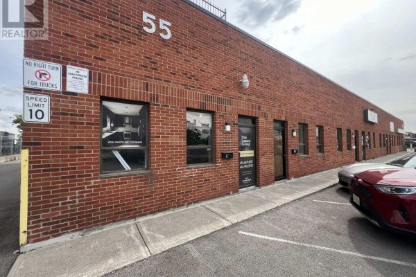 View of the commercial building exterior from the side, showing parking area and neighboring structures. - A1 - 55 Selby Road, Brampton