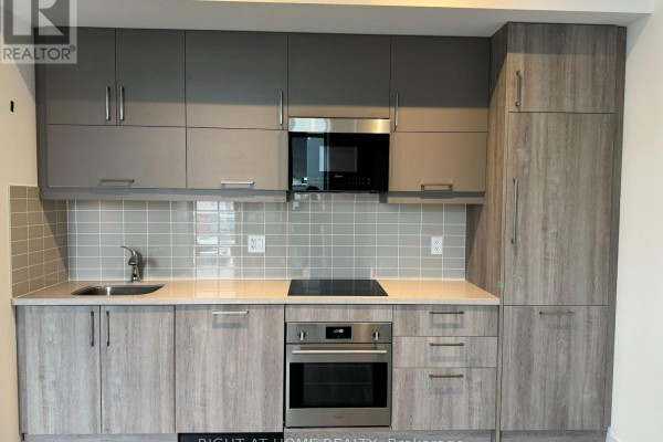 Modern kitchen with grey and wood cabinets, stainless steel appliances, and tiled backsplash. - A1405 - 8119 Birchmount Road N, Markham
