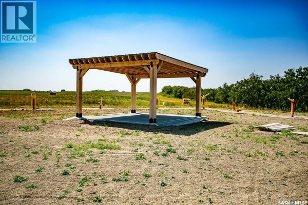 Wooden pergola with a concrete base sits in an open, grassy field under a bright blue sky. - A2 Valley View Estates, Longlaketon Rm No  219