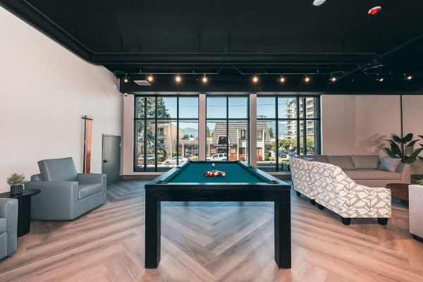Bright bedroom with a large picture window overlooking the city, a grey upholstered bed, and wood-toned nightstands. - A3 45815 Princess Avenue, Chilliwack Downtown, Chilliwack