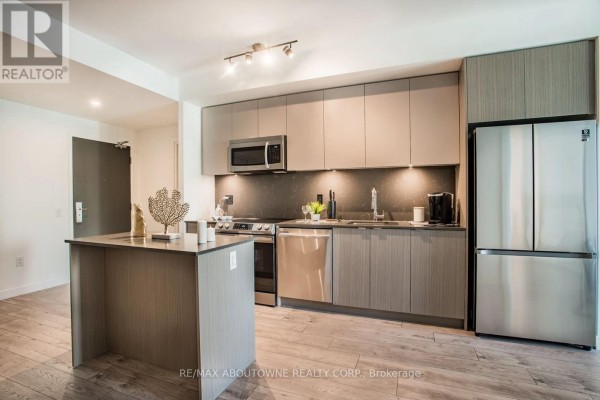 A contemporary kitchen with sleek, light wood cabinetry, stainless steel appliances, and a center island. - A303 - 125 Bronte Road, Oakville