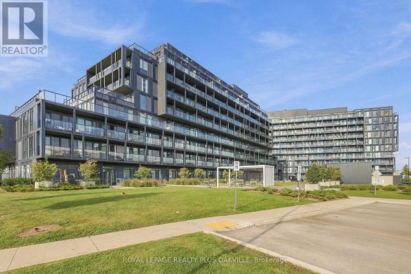 Exterior view of a modern apartment building with a manicured lawn in the foreground. - A312 - 3210 Dakota Common, Burlington