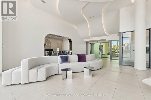 Contemporary lobby with curved white sofa, two silver side tables, and large glass windows. - A312 - 3210 Dakota Common, Burlington