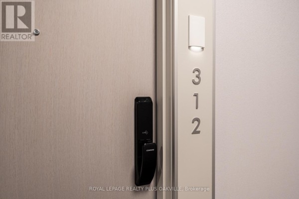 Close-up of a light wood apartment door with a digital lock and a number 312 sign. - A312 - 3210 Dakota Common, Burlington