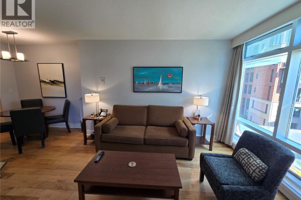 Living and dining area with sofa, coffee table, armchair, and a dining table. - A316 810 Humboldt St, Victoria