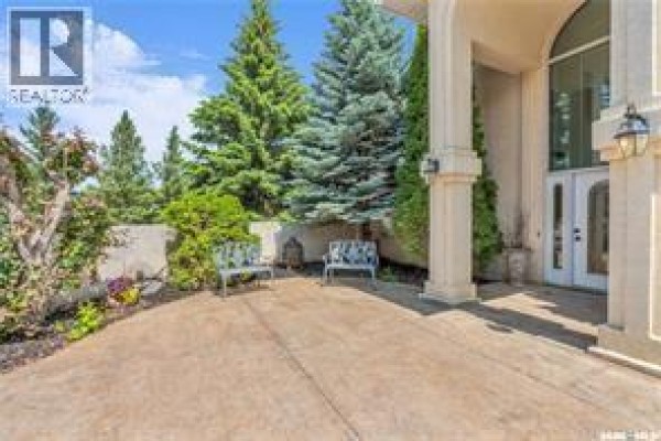 Outdoor seating area with two benches in front of a house entrance with trees. - Atcheynum Acreage, Battle River Rm No  438