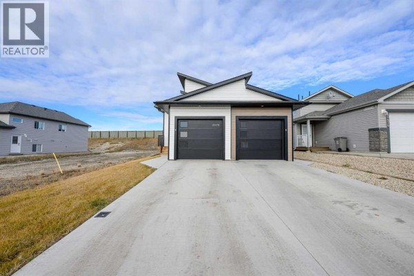 Concrete driveway leading to a modern house with two black garage doors. - B, 10478 131 Avenue, Grande Prairie