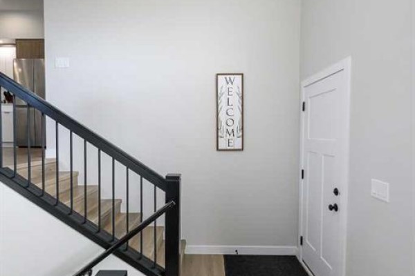 Entranceway with a white door, black banister staircase, and a welcome sign. - B, 10478 131 Avenue, Grande Prairie