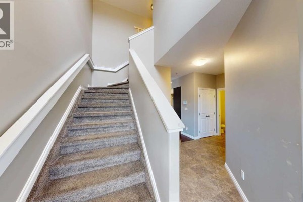 Carpeted staircase with beige walls and white handrails leads to the upper floor. - B, 13022 91a Street, Grande Prairie